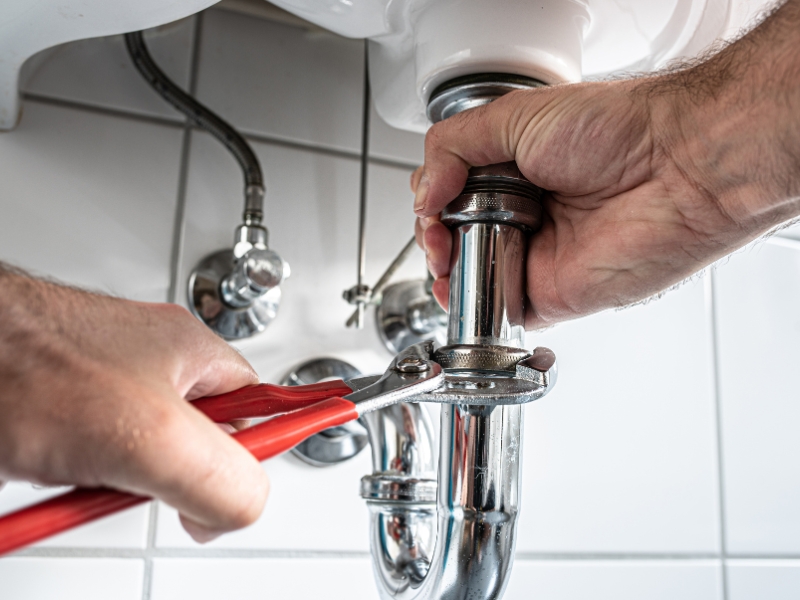 A plumber unclogs a u-bend on a sink