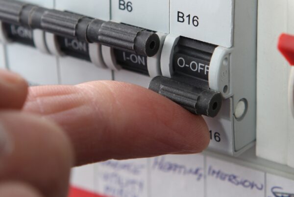 A finger flicking a switch on a fuse box