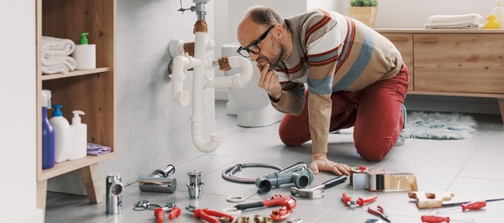 A confused man tries to carry out DIY plumbing