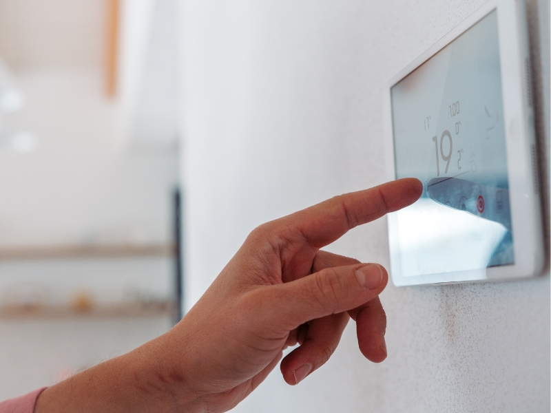 A hand operates an air con thermostat