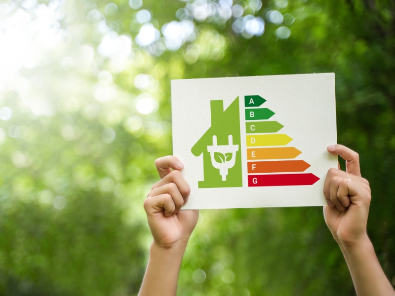 A green energy rating certificate held aloft by two hands