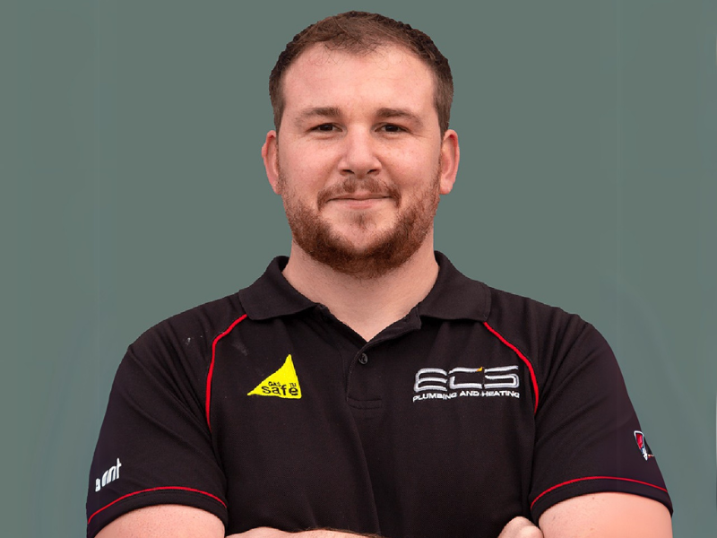 Chris from ECS Plumbing and Heating, standing confidently with arms crossed in a branded uniform